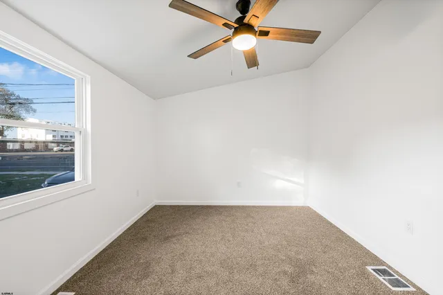 an empty room with a window and a fan