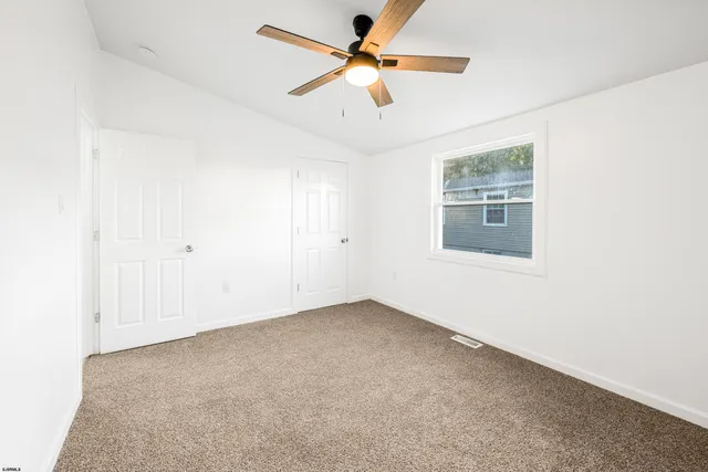 an empty room with windows and fan