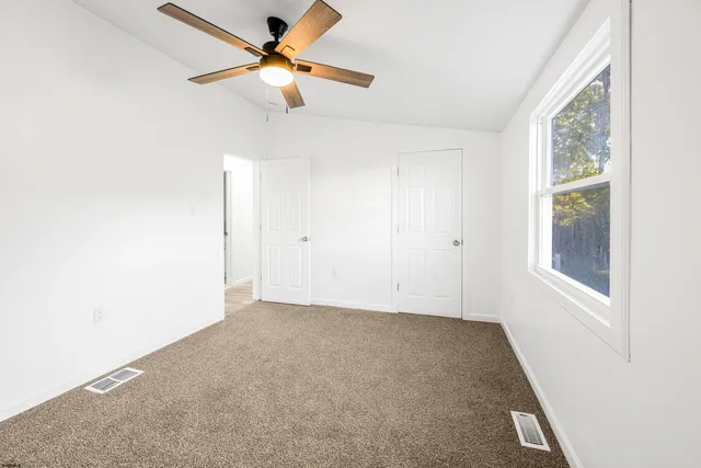 an empty room with a window and a fan