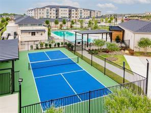 651 Watters Road, Unit 8206 Allen, TX 75013 - Photo 19 of 20 Outdoor recreational tennis court with perimeter fencing, adjacent swimming pool, manicured landscaping, and nearby multi-story building