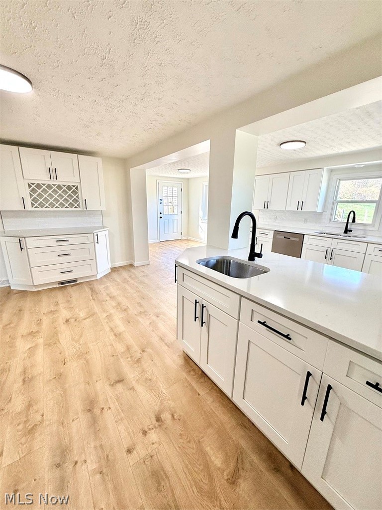 144 Aberdeen Road Steubenville, OH 43953 - Photo 13 of 34 Kitchen featuring white cabinetry, a textured ceiling, light stone counters, light wood-style flooring, and dishwasher