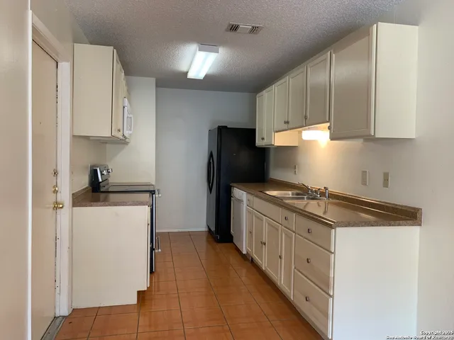 a kitchen with granite countertop a refrigerator stove and sink