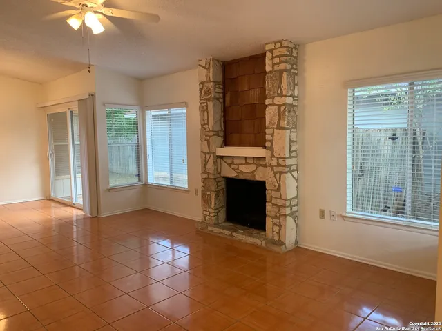 an empty room with windows and fireplace