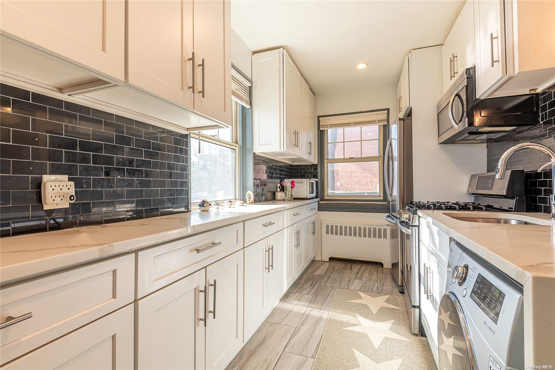 255-15 61st Avenue, Unit LOWR Queens, NY 11362 - Photo 1 of 1 a kitchen with stainless steel appliances a sink dishwasher a stove a microwave and wooden cabinets
