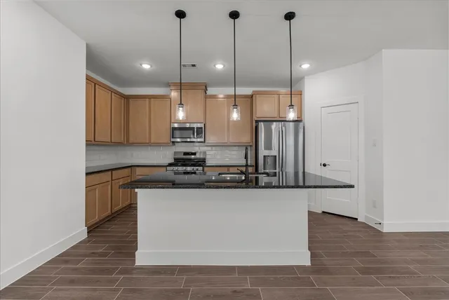 a kitchen with stainless steel appliances granite countertop a sink a stove and a refrigerator