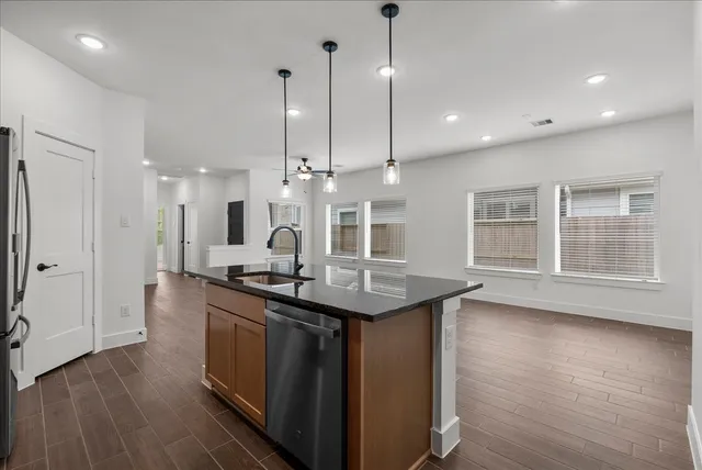 a kitchen with stainless steel appliances granite countertop a sink a stove and a wooden floor