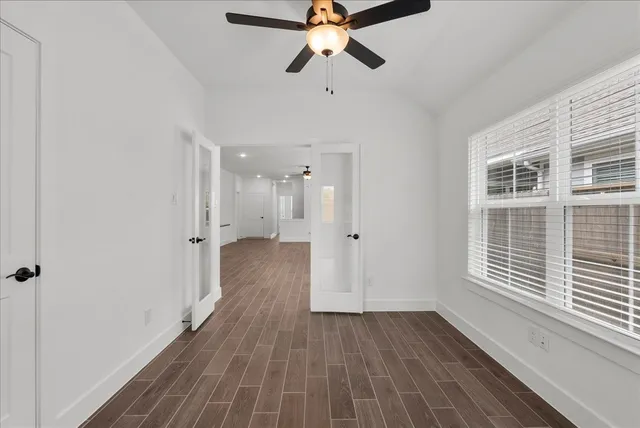 a view of empty room with wooden floor and fan