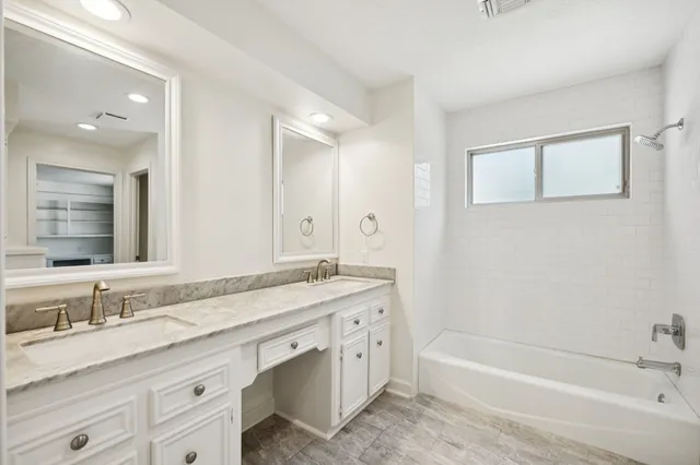 a bathroom with a granite countertop bathtub sink double and mirror