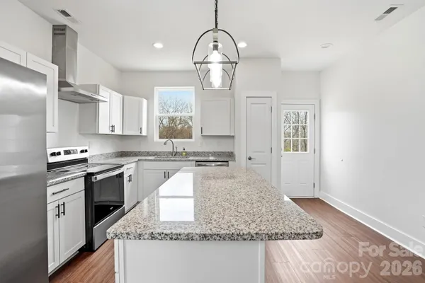a kitchen with kitchen island granite countertop stainless steel appliances a stove refrigerator and cabinets