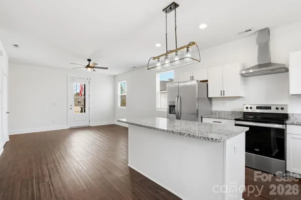a kitchen with stainless steel appliances granite countertop a sink a stove and a wooden floors