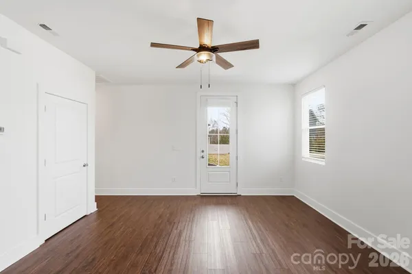 an empty room with wooden floor ceiling fan and windows