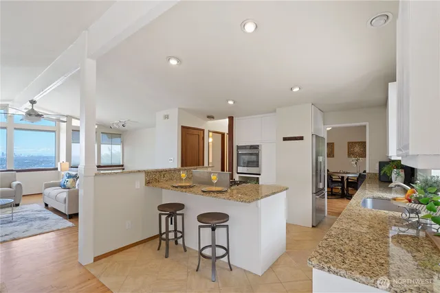 a kitchen with kitchen island granite countertop a stove a sink a oven and a dining table with wooden floor