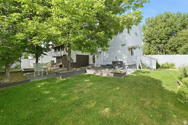 1464 990 West Provo, UT 84601 - Photo 38 of 41 Expansive rear yard featuring mature trees, a manicured lawn, a white privacy fence, a concrete patio, and dark-stained wood planter boxes