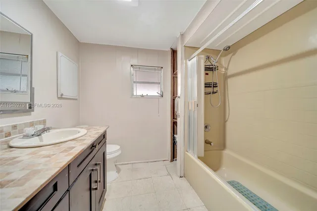 a bathroom with a granite countertop sink a toilet and shower