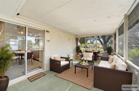 a living room with furniture a floor to ceiling window and potted plant