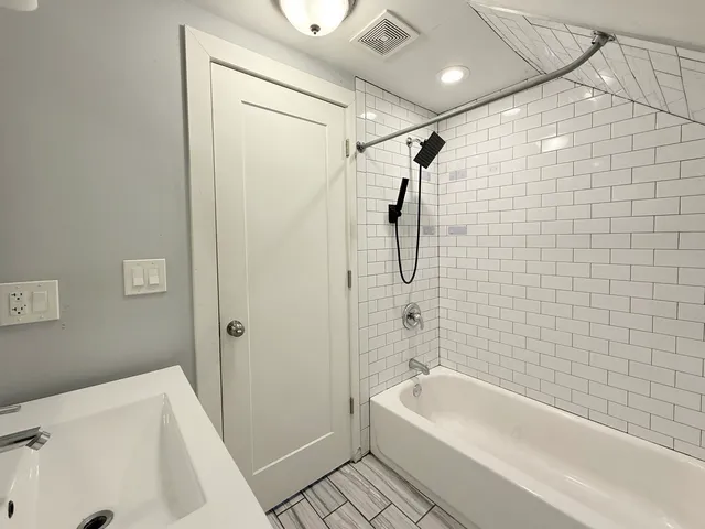 a bathroom with a tub a sink a window and a shower