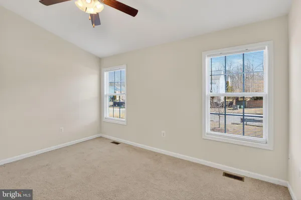 an empty room with chandelier fan and windows