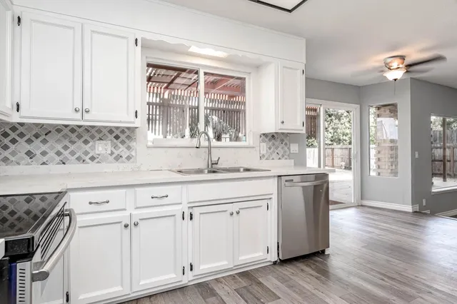 a kitchen with stainless steel appliances granite countertop a sink and cabinets with wooden floor