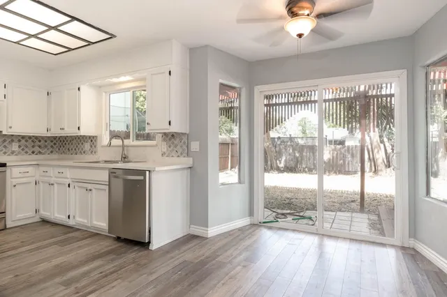 a view of a kitchen with a sink dishwasher wooden floor and a large window