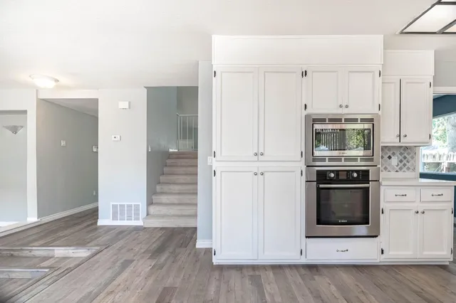 a kitchen with stainless steel appliances a stove a white cabinet and a microwave