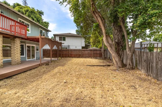 a view of a house with a yard and large tree