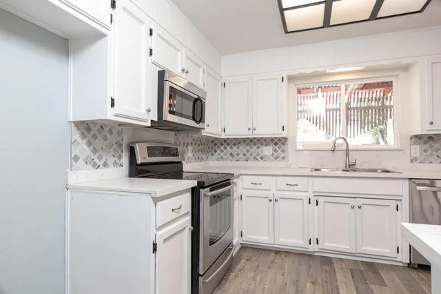 a kitchen with stainless steel appliances granite countertop a stove a sink and white cabinets