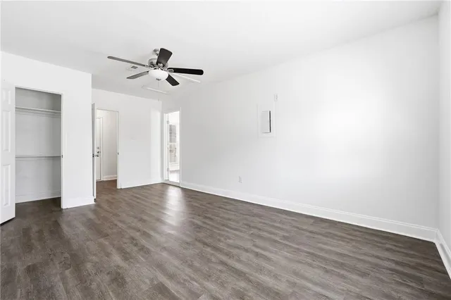 an empty room with wooden floor ceiling fan and windows