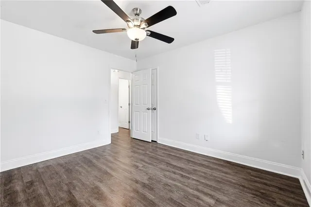 an empty room with wooden floor and ceiling fan