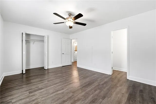 an empty room with wooden floor fan and windows