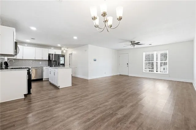 a view of kitchen with granite countertop a stove top oven a sink dishwasher and white cabinets with wooden floor