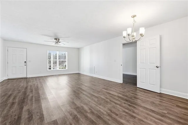 an empty room with wooden floor and chandelier