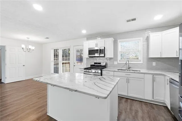 a kitchen with stainless steel appliances granite countertop a sink a stove a refrigerator cabinets and a window