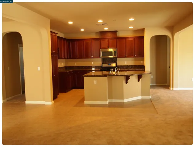 a view of kitchen with stainless steel appliances granite countertop refrigerator sink and stove