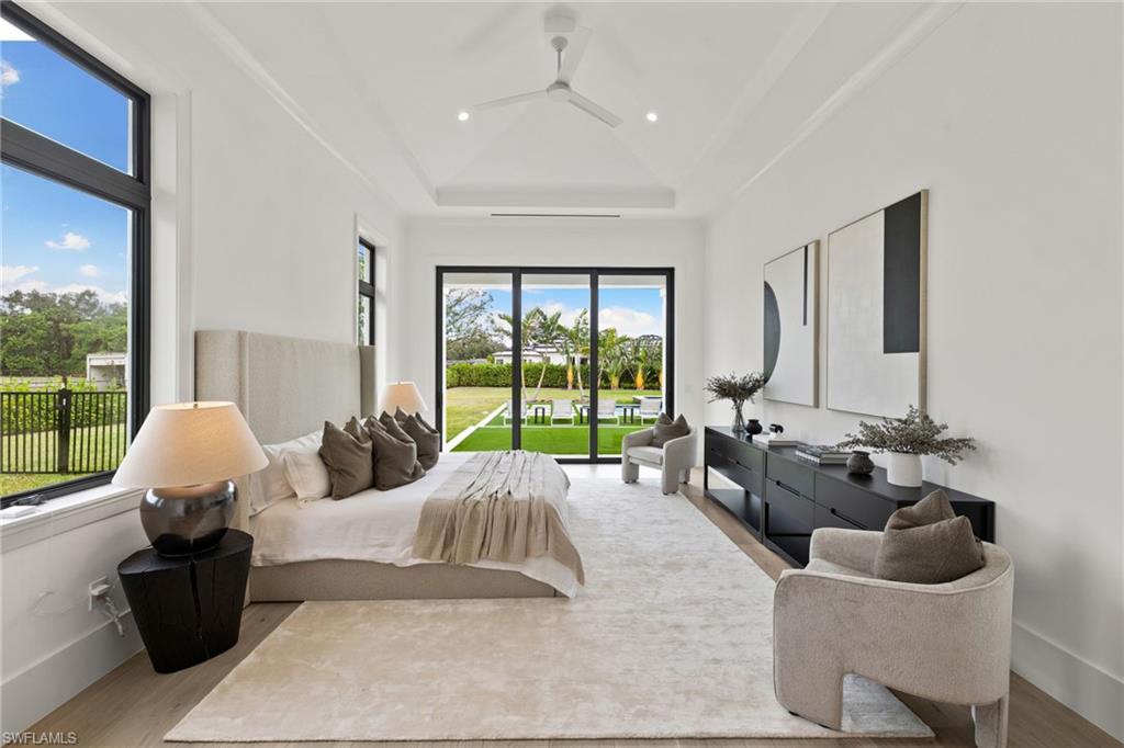 209 Tupelo Road Naples, FL 34108 - Photo 29 of 49 Bedroom with access to outside, a raised ceiling, and light hardwood / wood-style floors