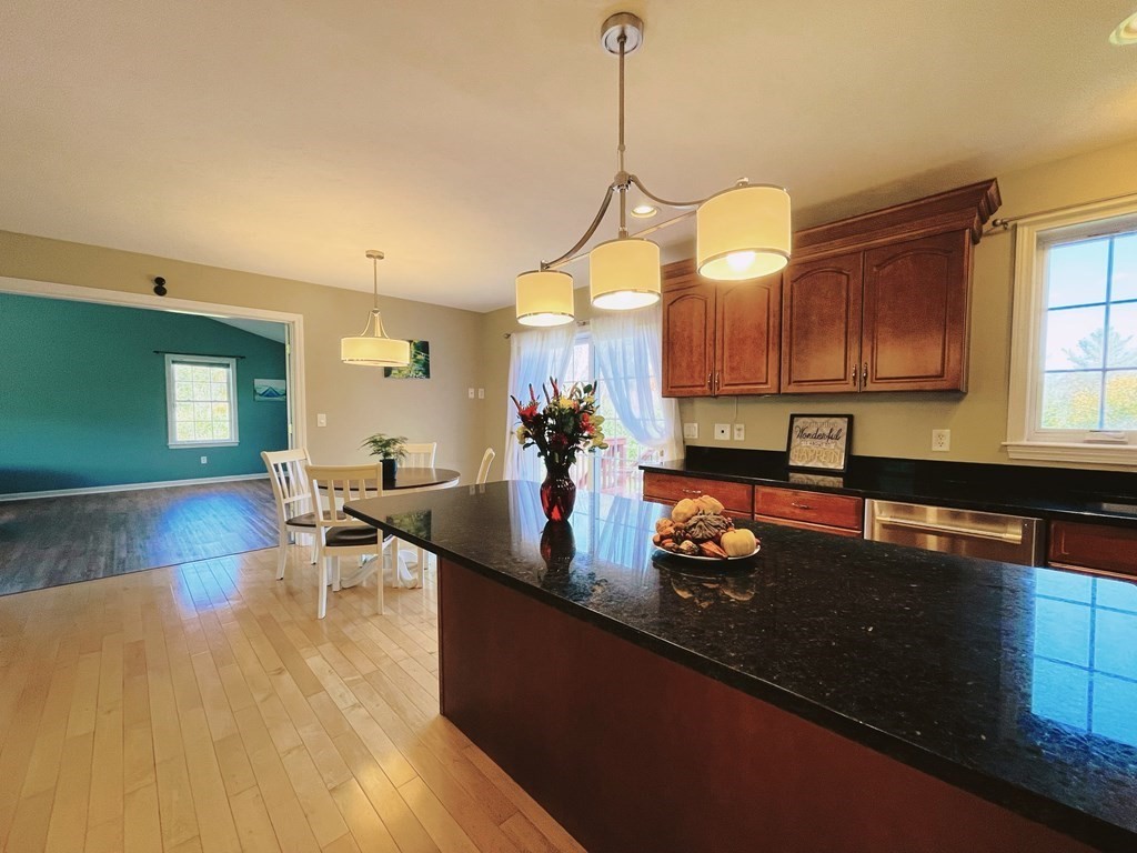 18 Windsor Road Shirley, MA 01464 - Photo 7 of 33 a kitchen with granite countertop a stove a sink a dining table and chairs with wooden floor