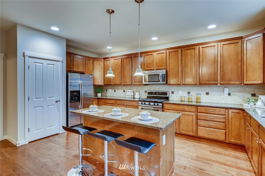 22325 36th Avenue Southeast Bothell, WA 98021 - Photo 7 of 22 a kitchen with stainless steel appliances granite countertop a refrigerator a sink dishwasher a stove and white cabinets with wooden floor
