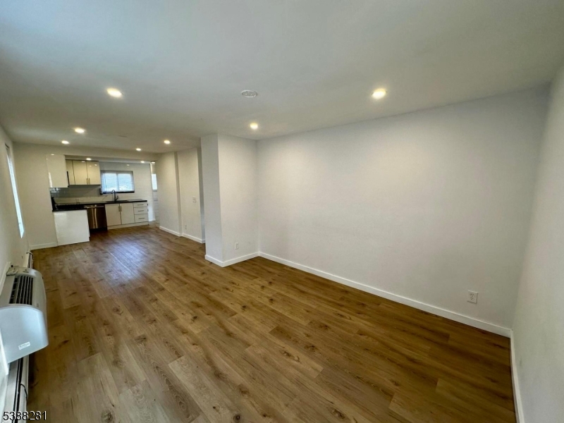 9 Fraser Street, Unit 2 Woodbridge, NJ 08863 - Photo 5 of 16 an empty room with wooden floor and a kitchen