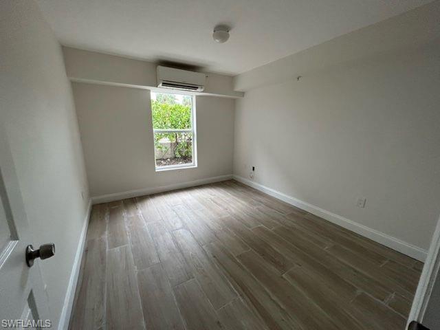 1555 Blue Point Avenue, Unit 3 Naples, FL 34102 - Photo 2 of 9 Spare room with a wall mounted air conditioner and hardwood / wood-style flooring
