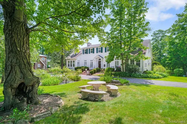 a front view of a house with garden and trees