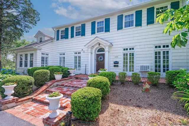 a view of a brick house with a yard and plants