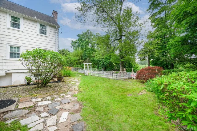 a backyard of a house with table and chairs plants and large trees