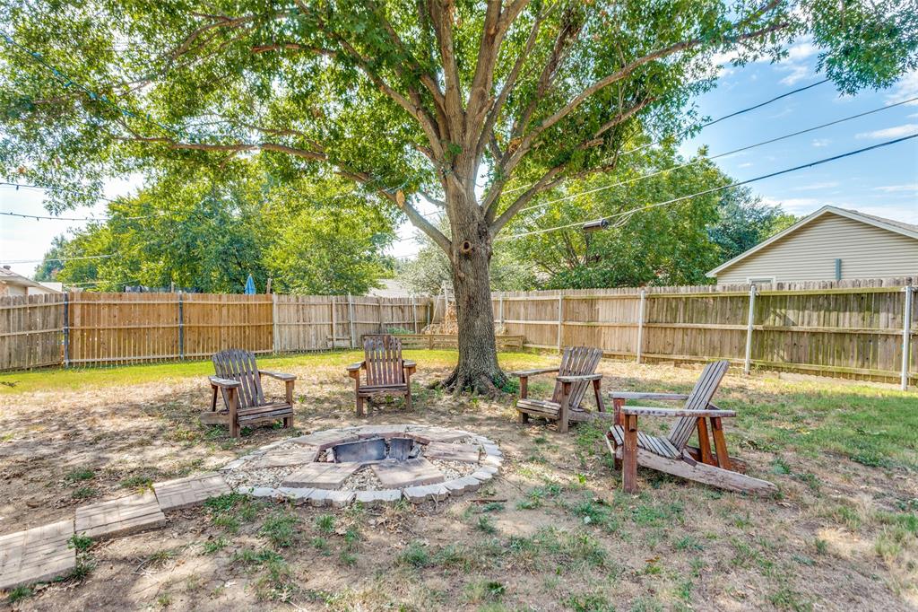 825 Blue Ridge Drive Burleson, TX 76028 - Photo 23 of 25 Fenced backyard featuring an outdoor fire pit and a patio with a large tree in which to provide shade from the hot Texas sun. Plenty of space to relax after a hard day...or host a cookout with family and friends .
