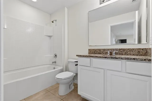 a bathroom with a granite countertop toilet sink and mirror