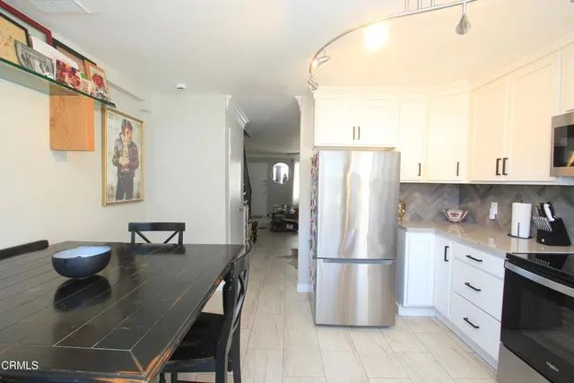 a kitchen with stainless steel appliances granite countertop a refrigerator a stove a sink a dining table and chairs