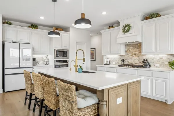a kitchen with stainless steel appliances granite countertop a kitchen island a stove a sink a dining table and chairs
