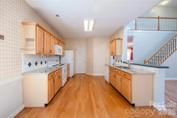 a large kitchen with stainless steel appliances granite countertop a lot of counter space and wooden floors