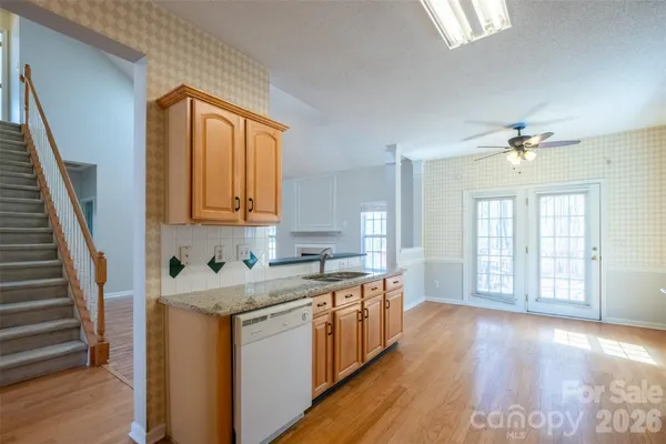 a view of a kitchen with a sink and dishwasher with wooden floor