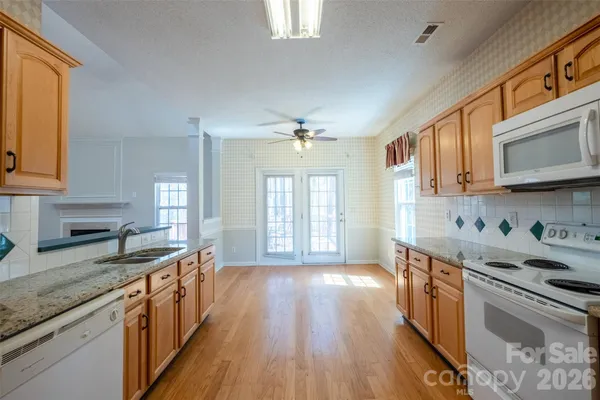 a kitchen with stainless steel appliances granite countertop hardwood floor sink stove and wooden cabinets