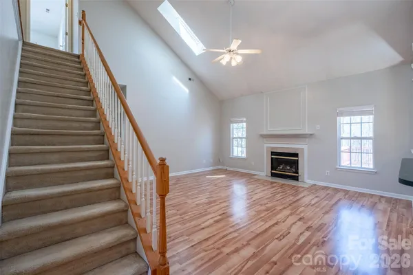 a view of an empty room with wooden floor fireplace and a window