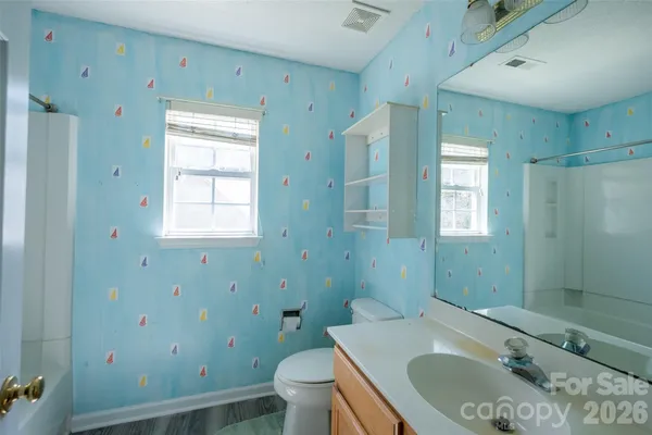 a bathroom with a granite countertop sink a toilet and shower